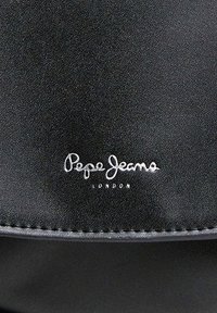 Crna torba od umjetne kože sa šavovima i bijelim logotipom "Pepe Jeans London" sprijeda. Glatka tekstura s jednostavnim dizajnom.