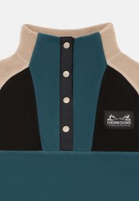 Pullover in pile con pannelli turchese, neri e beige. Presenta un colletto con zip, bottoni a pressione e una patch con logo con design di montagna.