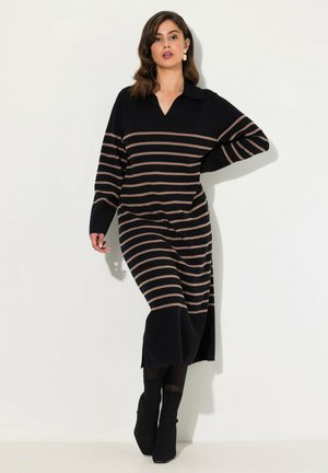 Schwarz und tan gestreiftes gestricktes Midikleid mit V-Ausschnitt und Kragen, ausgestattet mit langen Ärmeln und seitlichen Schlitzen, kombiniert mit schwarzen Stiefeletten.