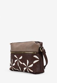 Bolso cruzado de cuero marrón con un patrón acolchado y acentos florales blancos; cuenta con un compartimento con cremallera y una correa desmontable.