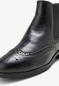 Svarta läderankelstövlar med en slät finish, brogue-detaljer med perforeringar och elastiska sidopaneler för en tajt passform.