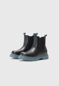 Botas de ankle de couro preto com painéis laterais elásticos, apresentando uma aba de puxar azul e solas de borracha chunky de azul claro.