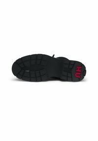 Talpa de sneaker neagră cu cauciuc texturat. Prezintă un profil cu model, un logo proeminent în roșu și o finisare netedă, mată.