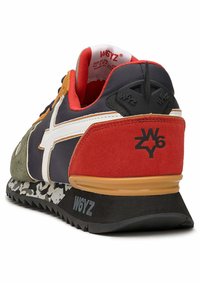Sneaker s kombinací materiálů, včetně námořnického síťovaného materiálu, zelené semišové kůže a červených akcentů. Bílý detail loga a texturovaná černá podešev s grafikou.
