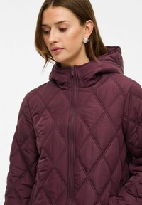 Sivá prešívaná puffer bunda s kapucňou. Obsahuje zips, textúru so šikmým vzorom a hladký syntetický materiál.