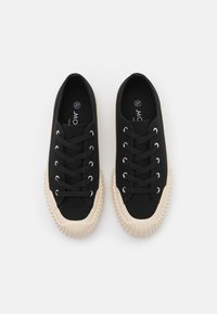 Baskets en toile noire avec semelles en caoutchouc beige, bout rond, œillets et lacets plats. Taille 37 indiquée à l'intérieur. Semelle extérieure texturée pour une meilleure adhérence.