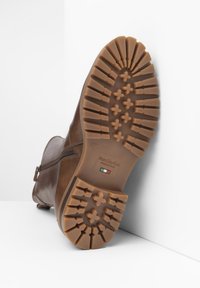 Bottines en cuir marron avec une semelle en caoutchouc texturée dotée d'un motif de crampons, fermeture éclair latérale et logo sur la semelle intermédiaire.