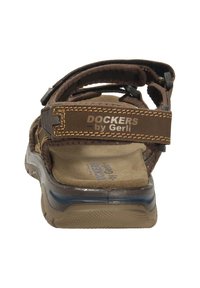 Brown sandal with adjustable straps, rubber sole, textured footbed, and “Dockers by Gerli” branding on the heel and strap.