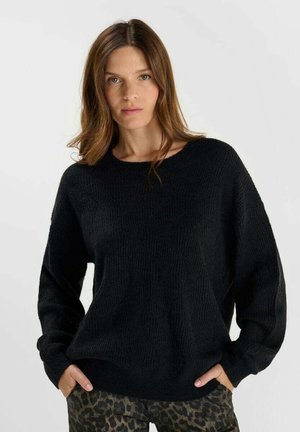 Black knit sweater with a textured pattern, wide sleeves, and a relaxed fit, paired with leopard print pants. Soft material.