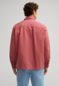 Roodbruine shirt met een relaxte pasvorm, lange mouwen en knoopmanchetten. Gemaakt van zachte stof, met een klassieke kraag en rugstuk.