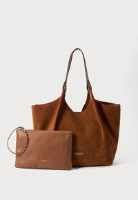 Bruine suede schoudertas met twee handvatten en een grote opening, samen met een kleinere bruine leren pouch met een polsbandje en een rits.
