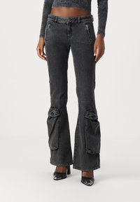 Pantalons en denim noir évasés avec des poches de style cargo, des accents zippés et une texture usée. Caractéristiques : taille mi-haute et jambes larges.