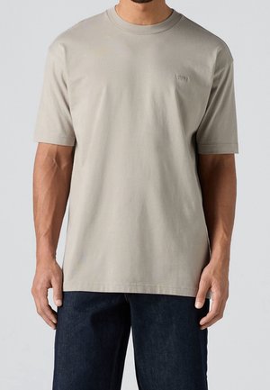 T-shirt en coton gris clair avec un col rond et des manches courtes. Présente un petit logo sur la poitrine et une coupe décontractée.