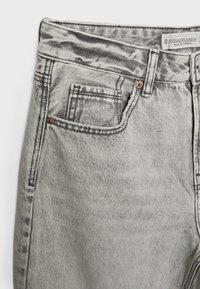 Jean en denim gris taille haute avec poches avant, passants de ceinture, rivets en cuivre et étiquette de la marque Stradivarius à l'intérieur de la ceinture.