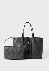 Zwarte gestructureerde tote bag met gouden hardware en gestreept detail, gecombineerd met een kleinere zwarte ritsportemonnee. Beide zijn voorzien van het 'GUESS' logo.