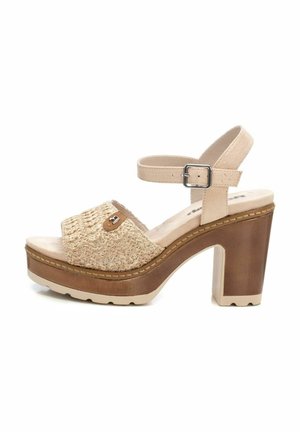 Sandalias de plataforma beige con textura trenzada, tira ancha y hebilla adjustable en el tobillo. Tacón de bloque de madera con un acabado oscuro y suave.