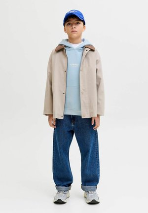 Bež jakna z rjavim ovratnikom, svetlo modra kapa, modra kapa, ohlapne modre kavbojke in sivi športni copati. Minimalističen dizajn, priložnostna prileganje.