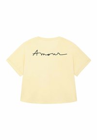T-shirt giallo oversize con scollatura rotonda, caratterizzato dalla scritta "Amour" in corsivo nero sul retro.