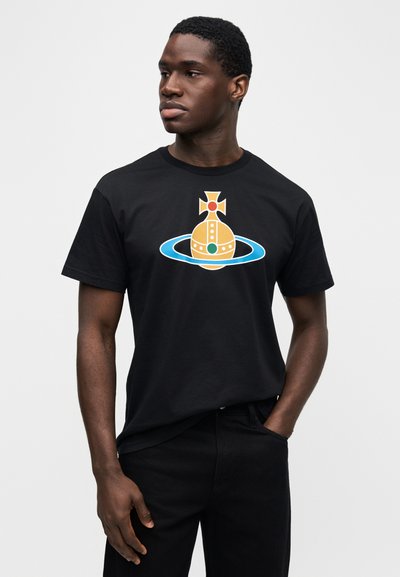 Μαύρο βαμβακερό μπλουζάκι με κίτρινο και μπλε γραφικό σχέδιο σφαίρας και δακτυλίου, με έντονα χρώματα και γεωμετρικά μοτίβα.