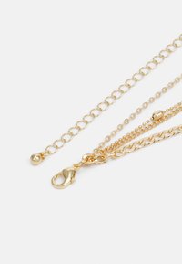 Gold layered chains featuring varying thicknesses, smooth textures, and a lobster clasp. Includes a round bead detail on one chain.