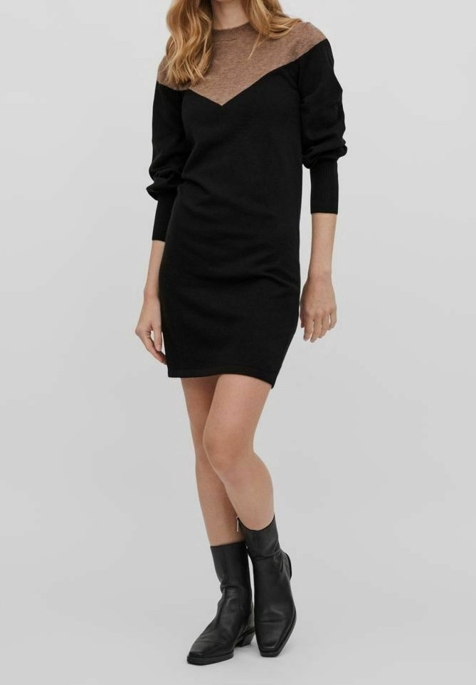 Schwarzes Kleid mit braunem strukturiertem Schulterbereich, langen Ärmeln, taillierter Passform, knielang, kombiniert mit schwarzen Stiefeletten.