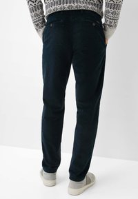 Pantaloni in corduroy verde scuro con finitura testurizzata, dotati di una vestibilità dritta, due tasche posteriori e sottili dettagli con bottoni.