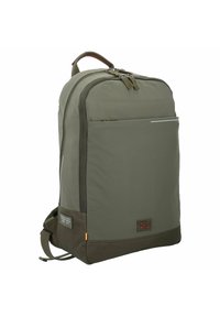 Sac à dos en nylon vert avec un dos matelassé, fermeture éclair, poche avant et patch logo. Présente un fond marron et des détails réfléchissants.