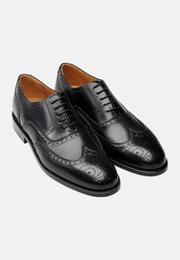 Scarpe eleganti in pelle nera con dettagli a perforazione brogue, design con lacci e finitura liscia. Forma classica con punta lucida.