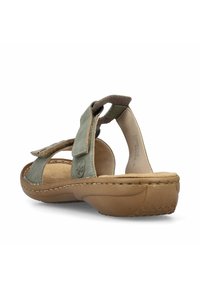 Grüne Wildleder-Sandale mit einer beige konturierten Sohle, verstellbarem Klettverschluss und gesteppten Details, die eine strukturierte Oberfläche zeigt.