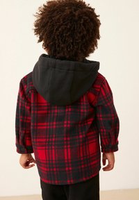 Röd och svart rutmönstrad fleecejacka med svart huva, som har långa ärmar och knappmanschetter, visad bakifrån.