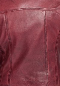 Giacca in pelle bordeaux con una superficie liscia, cuciture pronunciate e una forma strutturata con una finitura pulita.