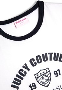 Vit t-shirt med kort ärm och svart rund halsringning. Tryckt logotyp med "Juicy Couture" och en fotbollscrest med stjärnor nedanför.