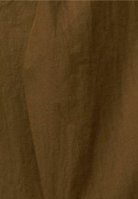Hnědá tkanina vzoru rybí kosti, texturovaná jemnými liniemi, s bohatým, tmavým odstínem a mírně pomačkaným vzhledem.
