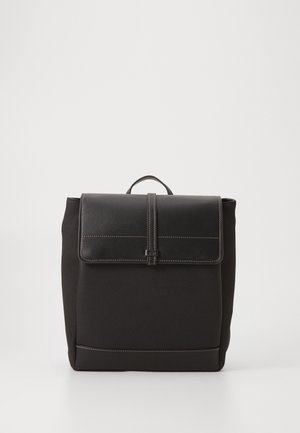 Czarny kwadratowy plecak z górnym uchwytem, przednia klapka zabezpieczona centralnym paskiem oraz widoczne białe przeszycia na krawędziach.