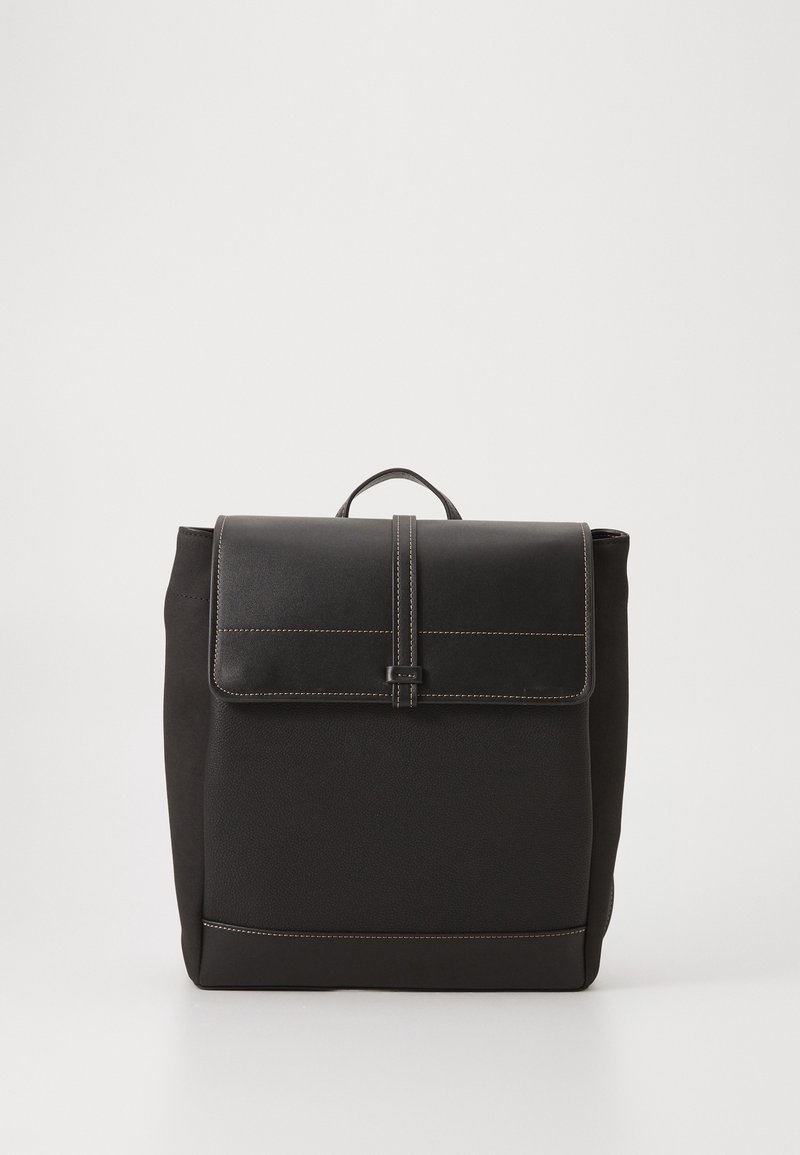 Sac à dos carré noir avec poignée supérieure, rabat avant sécurisé par une sangle centrale et coutures blanches visibles sur les bords.
