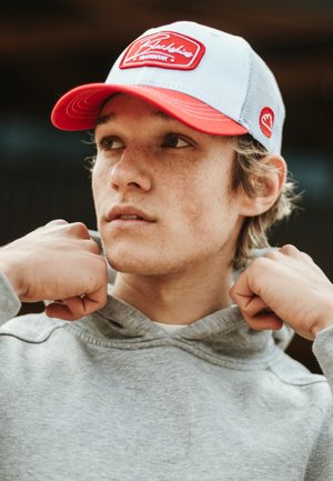 Hallitus hall hoodie koos nööriga, punase äärega müts, millel on valge paneel ja logo silti, tekstuuriga kude, inimene poseerimas käed kaela lähedal.