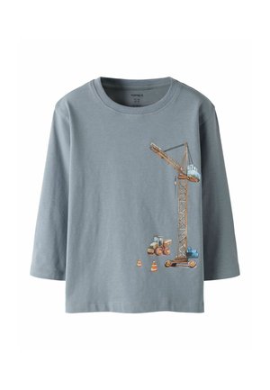 Chemise grise à manches longues avec un imprimé d'une grue de construction, un camion-benne et trois cônes de signalisation orange sur le bas droit à l'avant.