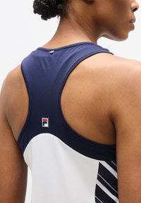 Débardeur sportif bleu marine et blanc à dos nageur, avec un tissu texturé et un petit logo Fila à l'arrière.