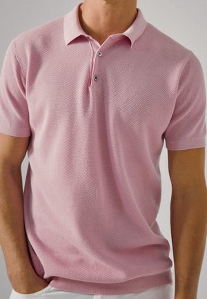 Polo shirt in zachtroze, gemaakt van gestructureerde stof. Heeft een klassieke kraag en een knoopsluiting met twee knopen. Korte mouwen, getailleerd ontwerp.