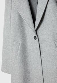 Grijze wollen jas met een brede revers, enkele zwarte knoopsluiting en twee zijzakken. Zachte textuur en gestructureerd ontwerp.