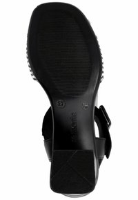 Pantofole nere con base in gomma testurizzata. Cinturino regolabile con fibbia argentata. Logo del marchio visibile sulla suola. Taglia contrassegnata come 37.