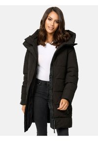 Black long puffer coat with a hood, featuring a zippered front and snap closures, quilted texture, and side pockets. Worn over a white top.