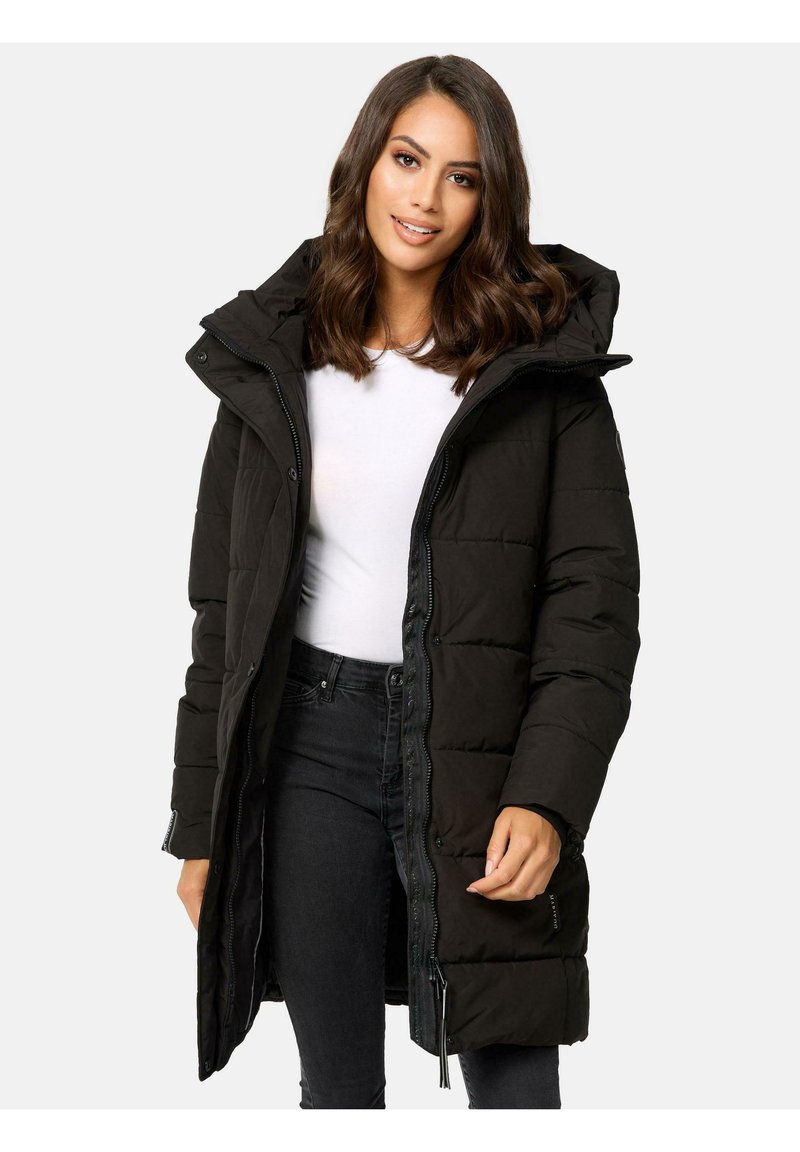 Black long puffer coat with a hood, featuring a zippered front and snap closures, quilted texture, and side pockets. Worn over a white top.