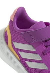 Fioletowy but sportowy z siateczkowym wierzchem, srebrnymi akcentami i teksturowanym, wyściełanym kołnierzem. Pasek na rzep i gumowa podeszwa.