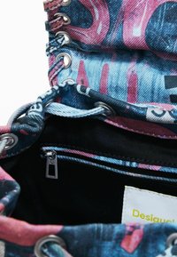Torba typu tote z denimu, z kolorowym graficznym nadrukiem, srebrnymi oczkami i ukrytą kieszonką na zamek błyskawiczny wewnątrz. Posiada kontrastowe czarne podszewkę.