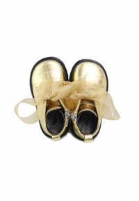 Zapatos metálicos de niño en color dorado con textura de cocodrilo, suelas de goma negra y detalles de cintas transparentes atadas en la parte delantera.