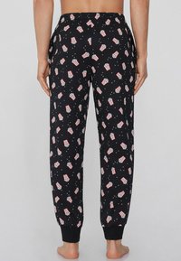 Pantalones de pijama negros con un diseño de palomitas en rojo y blanco, con una cinturilla elástica y puños ajustados. Tejido suave con una textura lisa.