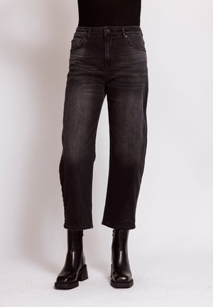 Lower body wearing black high-waisted cropped jeans and black heeled ankle boots against a plain background.