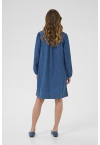 Denims kleita ar garajām piedurknēm, brīvu piegriezumu un ceļa garumu. Iezīmē klasisku zilu krāsu ar mīkstu tekstūru un izšūtu detaļu.