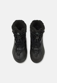 Schwarze Winterstiefel mit strukturierten Gummibezügen, gefütterten Oberteilen aus Fell und verstellbaren Schnürsenkeln. Sie verfügen über eine runde Zehenpartie und robuste Sohlen.